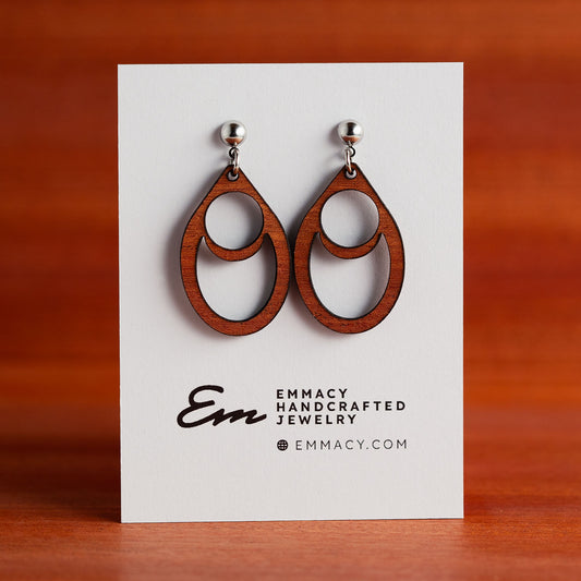 Laser cut wooden dangle earrings in the shape of a teardrop with circles and half moon cutouts.
