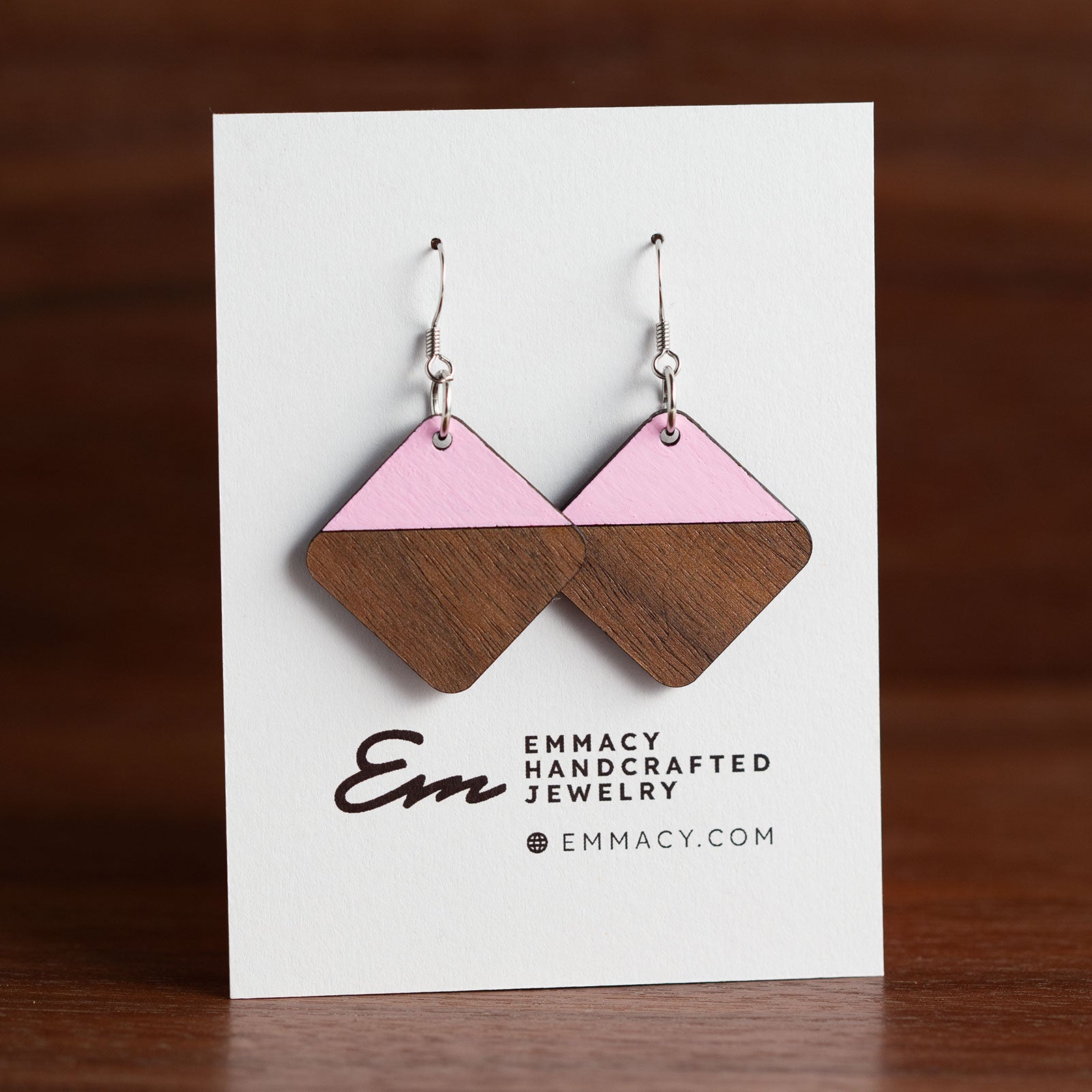 Laser cut wooden dangle earrings in the shaper of rounded diamonds with the top half painted pink.