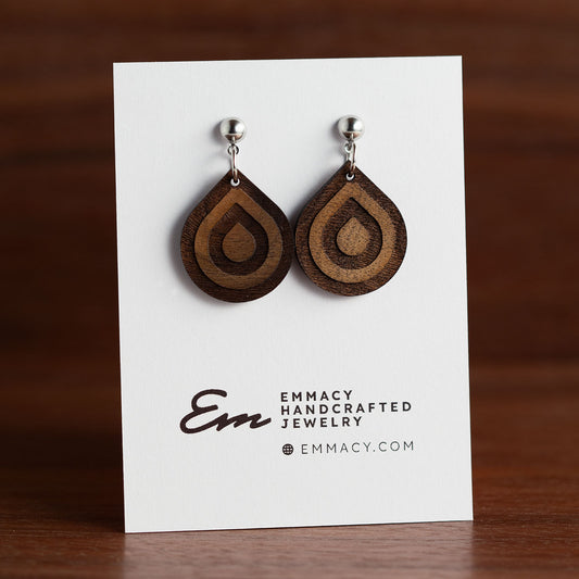 Laser cut wooden dangle earrings in the shape of a teardrop with engraved concentric teardrop shapes.
