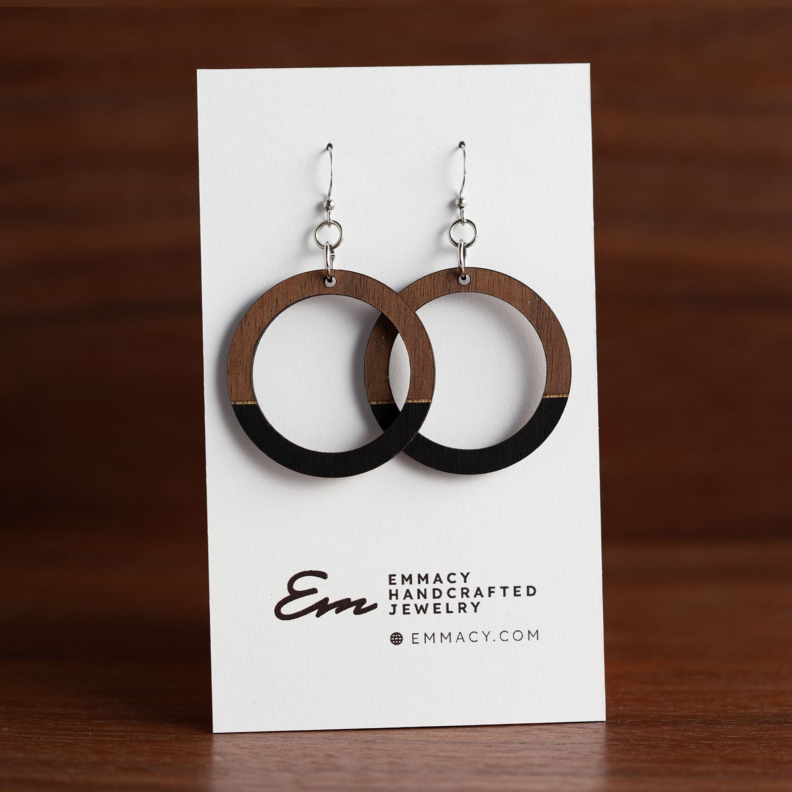 Laser cut wooden dangle earrings in the shape of a hoop with the bottom third painted black.