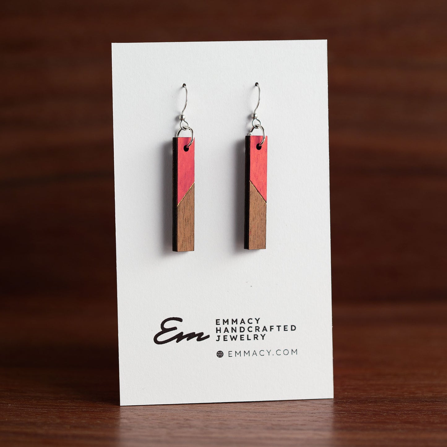 Laser cut wooden dangle earrings in the shape of a thin rectangle with the top half painted red.