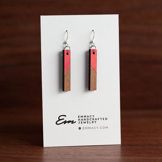 Laser cut wooden dangle earrings in the shape of a thin rectangle with the top half painted red.