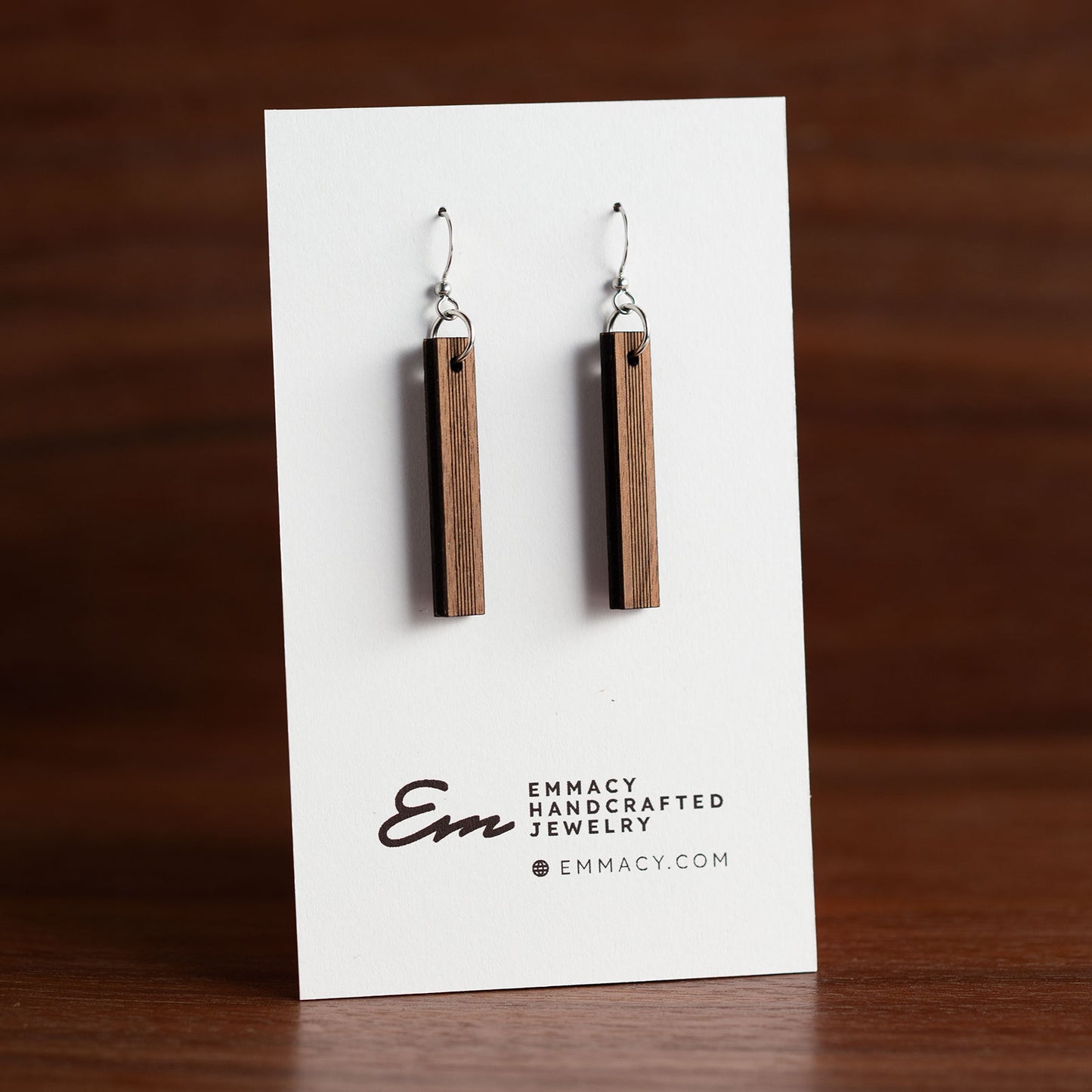 Laser cut wooden dangle earrings in the shape of a thin rectangle with score lines down the center third.