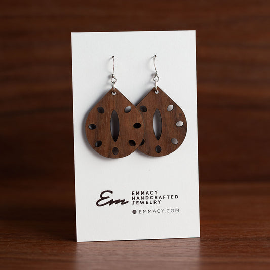 Laser cut wooden dangle earrings cut in the shape of a teardrop with a thin oval removed fro the center with oblong holes removed around the edges.