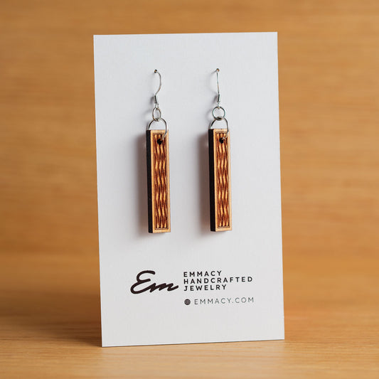 Laser cut wooden dangle earrings cut in the shape of thin rectangles with a basketweave pattern engraved in the middle.