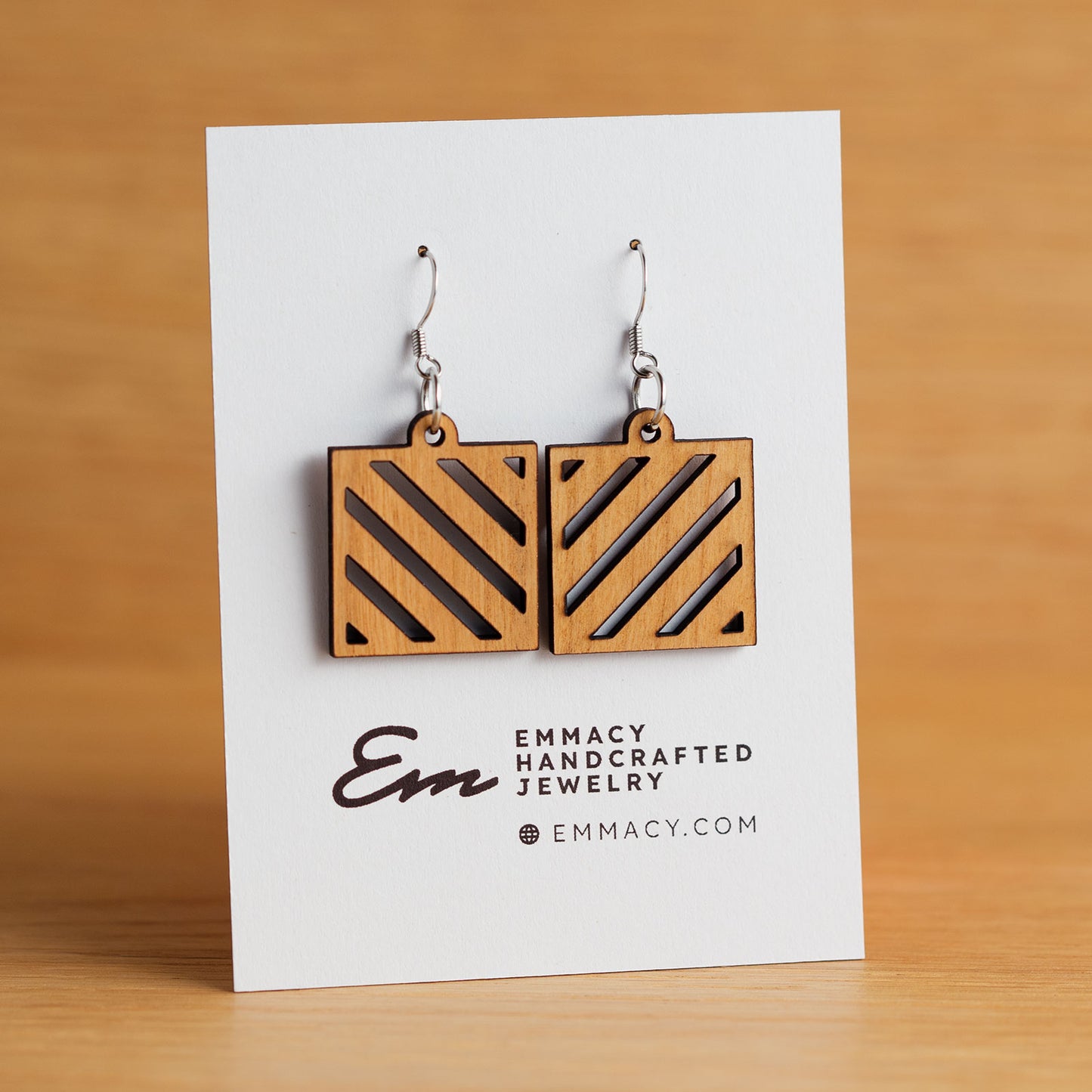 Laser cut wooden dangle earrings in the shape of a square with angled slat cutouts.
