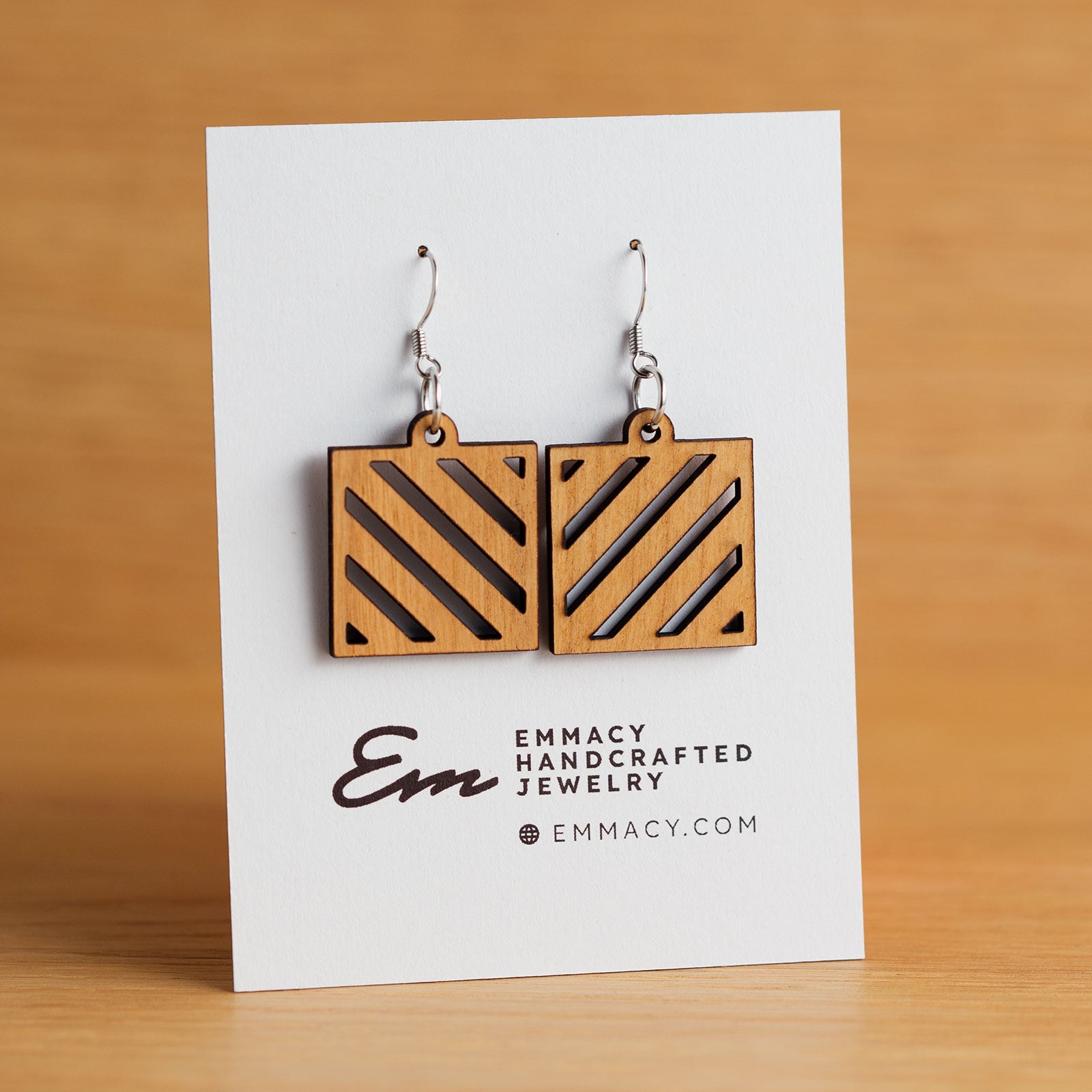 Laser cut wooden dangle earrings in the shape of a square with angled slat cutouts.
