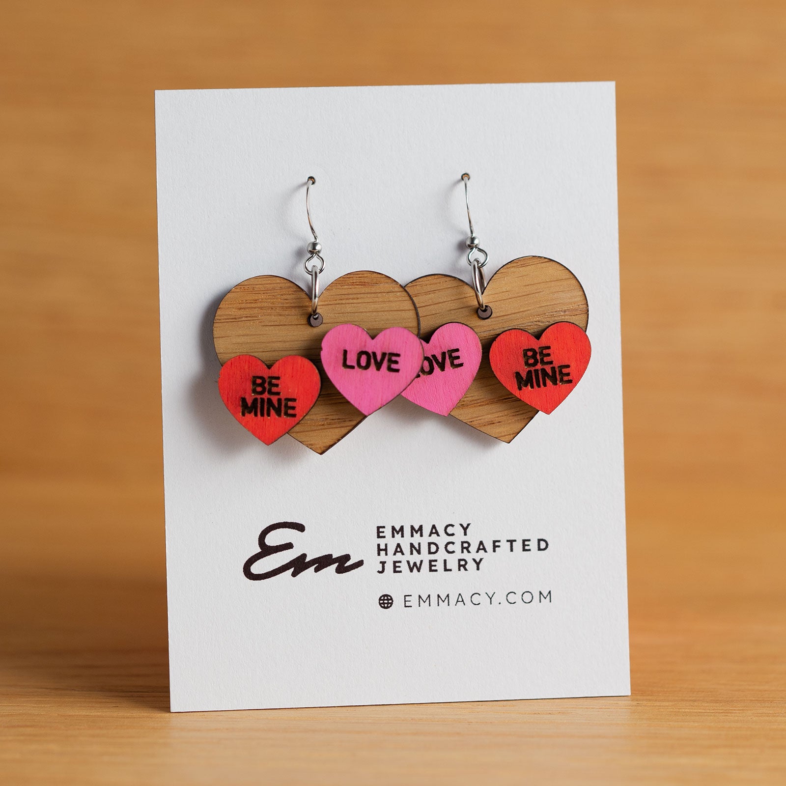 Laser cut wooden dangle earrings in the shape of a heart with two painted conversation hearts added.