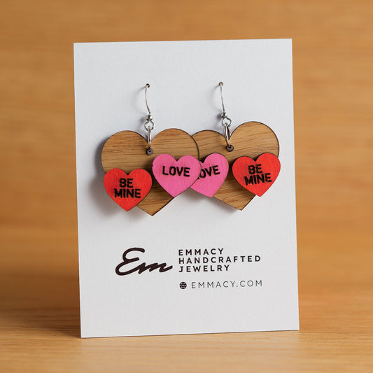 Laser cut wooden dangle earrings in the shape of a heart with two painted conversation hearts added.