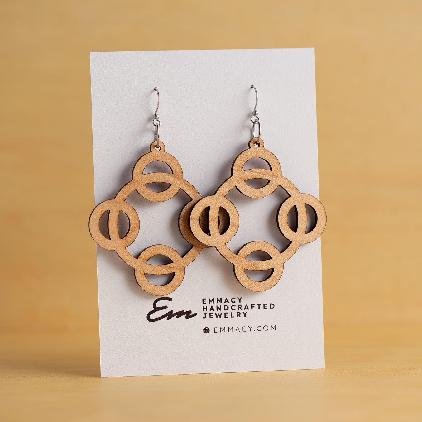 Laser cut wooden dangle earrings cut in the shape of four circles around a large center circle.