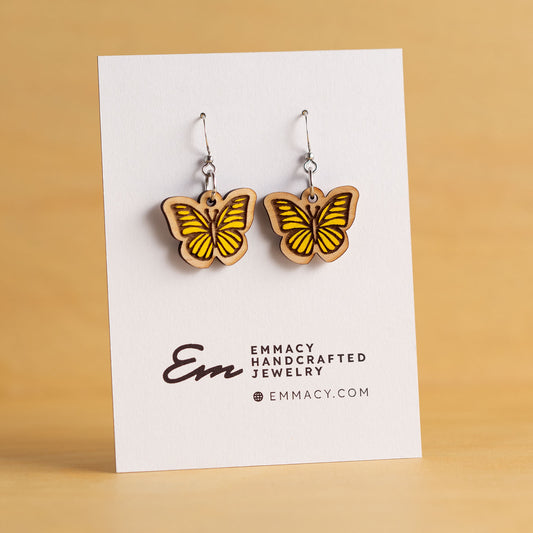 Laser cut wooden dangle earrings in the shape of a butterfly painted yellow.