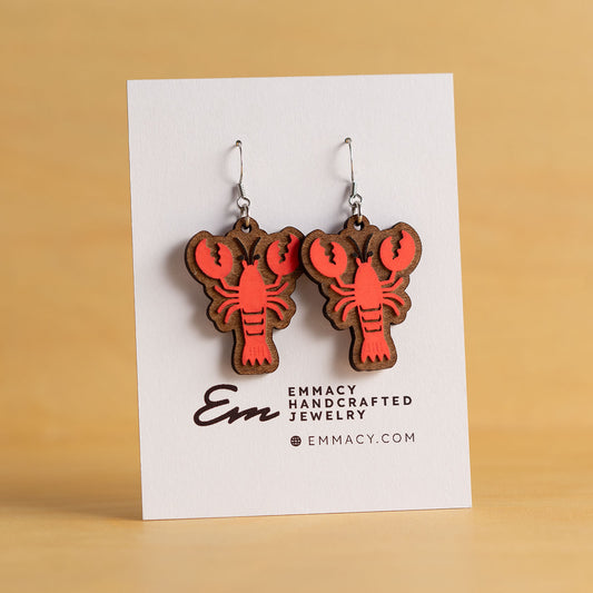 Laser cut wooden dangle earrings in the shape of a lobster painted red.