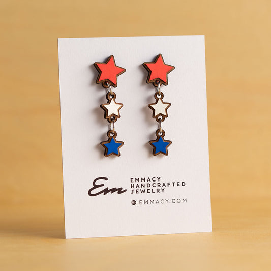 Laser cut wooden dangle earrings in the shape of three stars painted red, white, and blue.