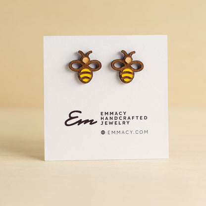 Laser cut wooden stud earrings in the shape of a bee with painted yellow stripes.