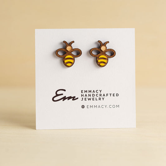 Laser cut wooden stud earrings in the shape of a bee with painted yellow stripes.
