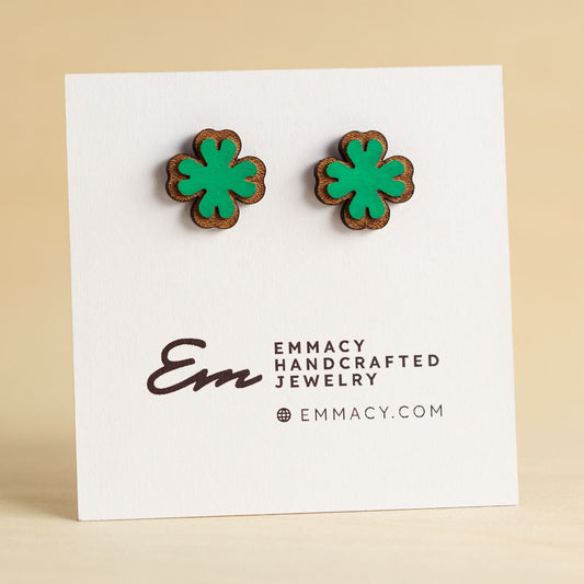 Laser cut wooden stud earrings in the shape of a four leaf clover painted green.