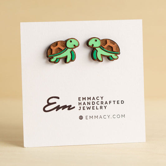 Laser cut wooden stud earrings in the shape of a sea turtle painted green and brown.