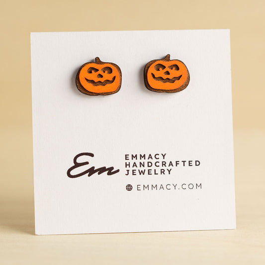 Laser cut wooden stud earrings in the shape of a jack-o-lantern painted orange.
