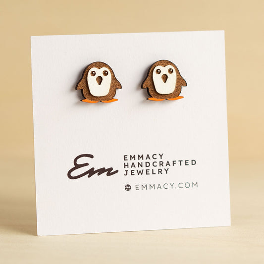 Laser cut wooden stud earrings in the shape of a penguin with a white painted chest.
