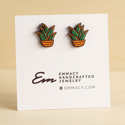 Laser cut wooden stud earrings in the shape of a potted snake plant painted green and orange.