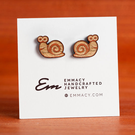 Laser cut wooden stud earrings in the shape of a snail with engraved details.