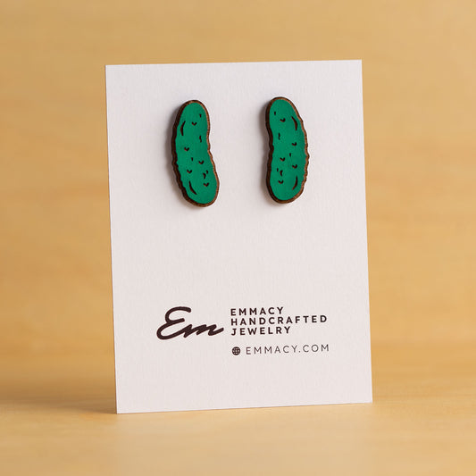 Laser cut wood stud earrings in the shape of a pickle painted green.